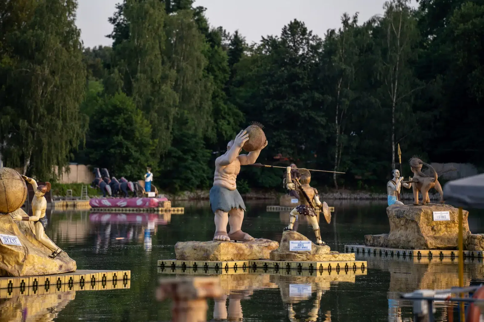 Figury greckich bohaterów na jeziorze w Parku Mitologii o zmierzchu